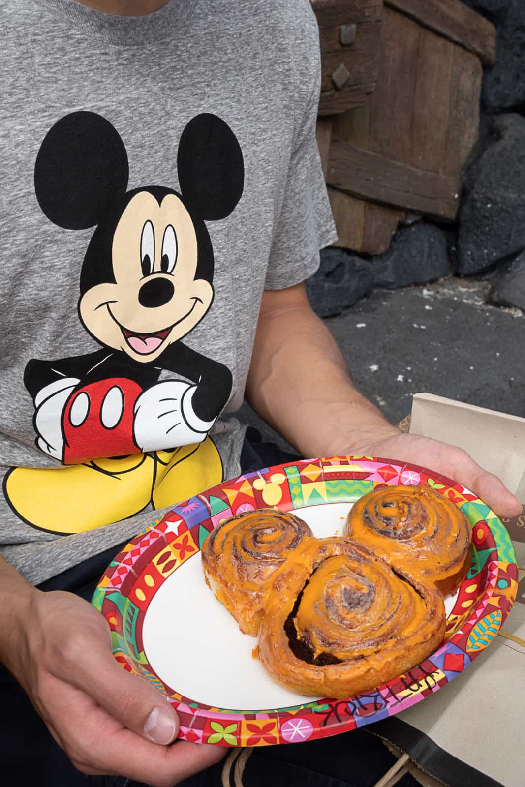 Disney Tourist Holding Mickey Cinnamon Roll with orange frosting for Halloween time